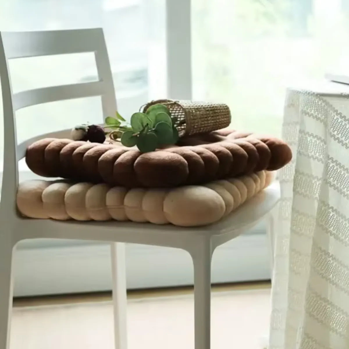 Deux coussins de chaise biscuit sur une chaise blanche, design moelleux , dans un décor lumineux et naturel.