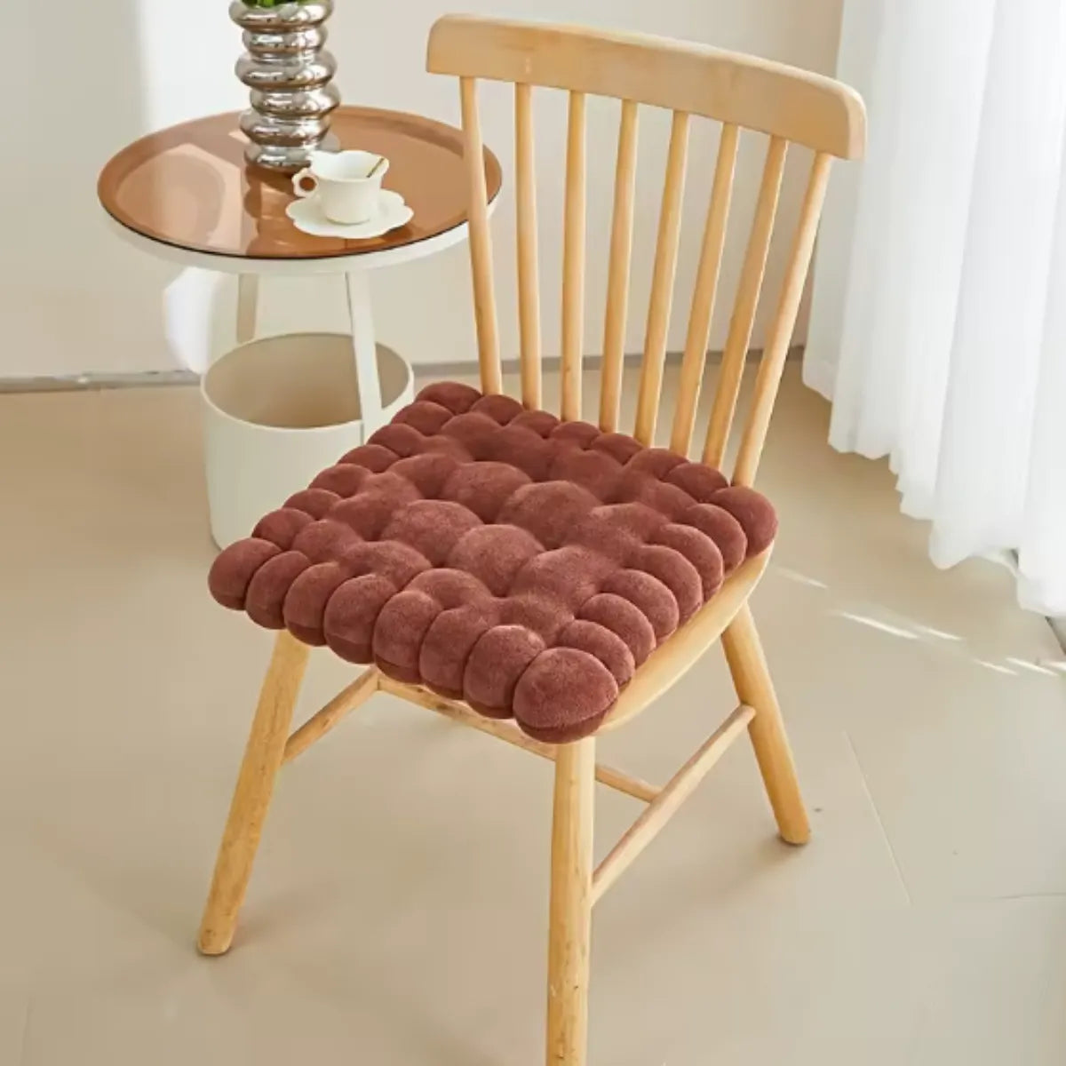 Coussin décoratif en forme de biscuit carré sur une chaise en bois à coté d'une petite table