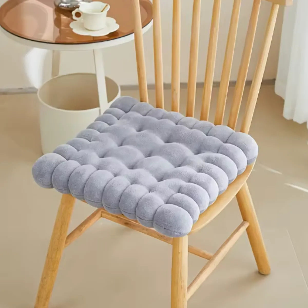 Coussin décoratif en forme de biscuit carré sur une chaise en bois à coté d'une petite table
