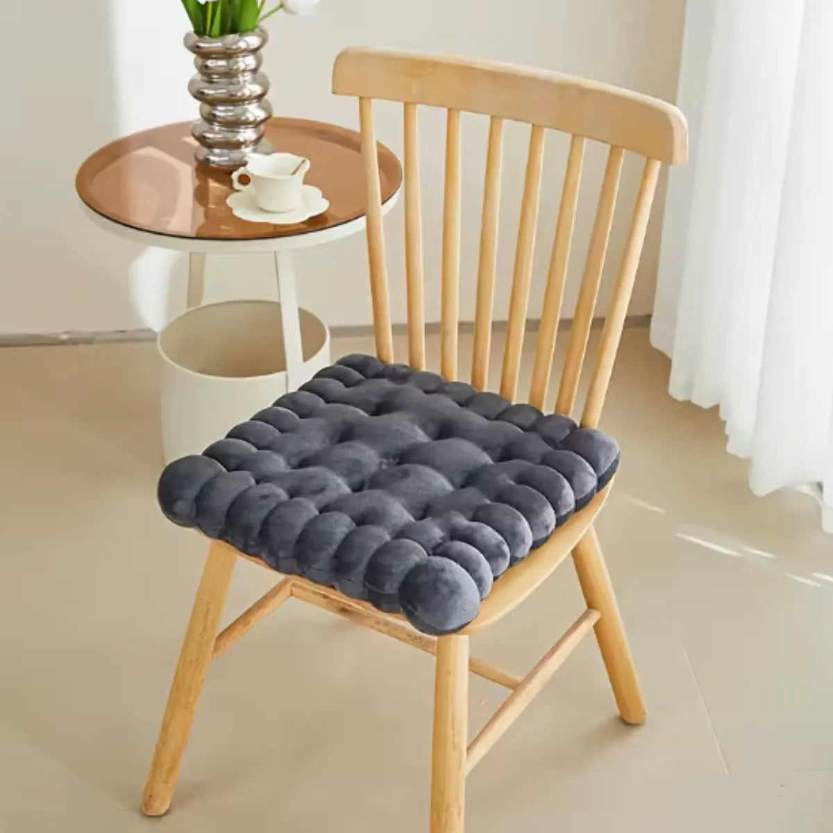 Coussin décoratif en forme de biscuit carré sur une chaise en bois à coté d'une petite table