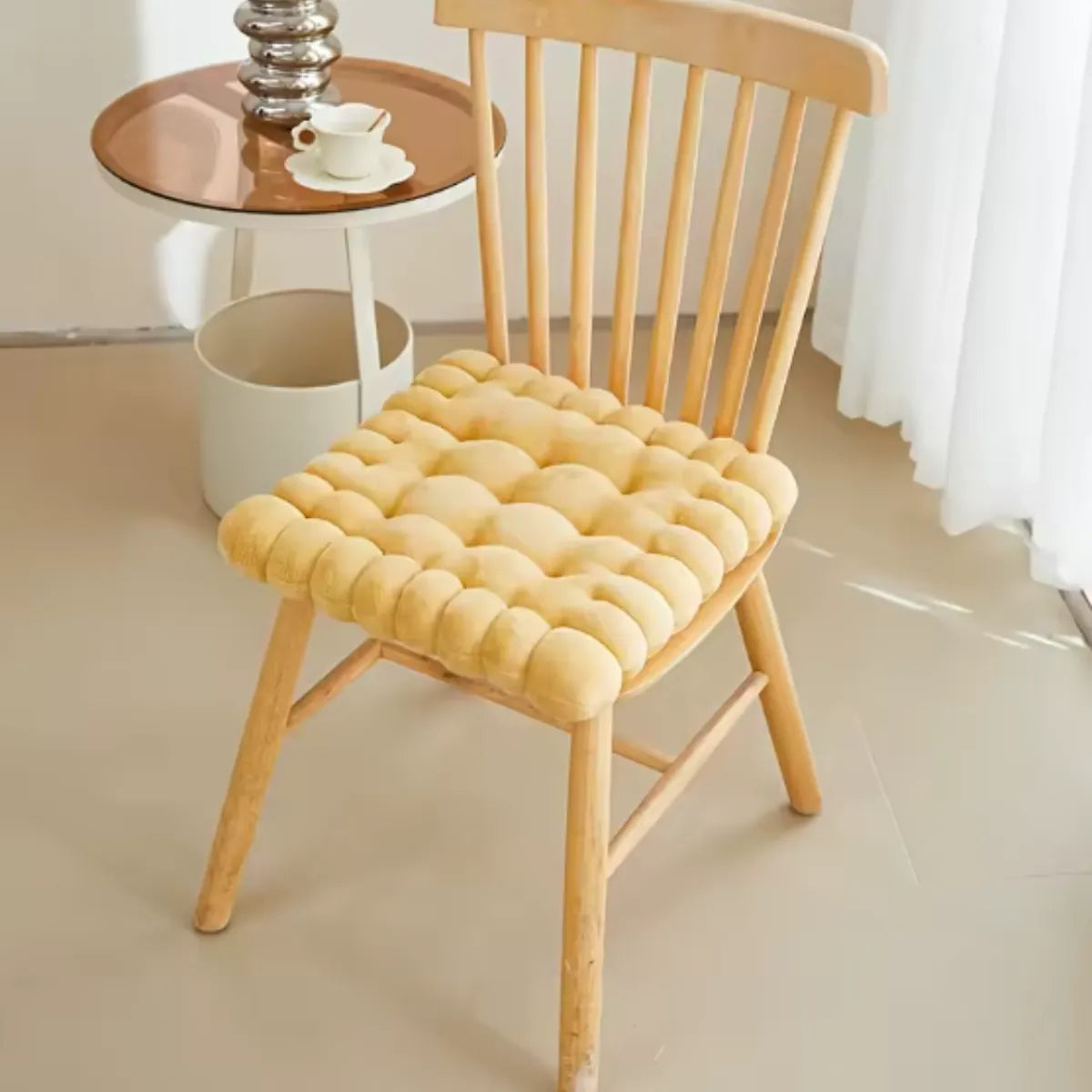Coussin décoratif en forme de biscuit carré sur une chaise en bois à coté d'une petite table