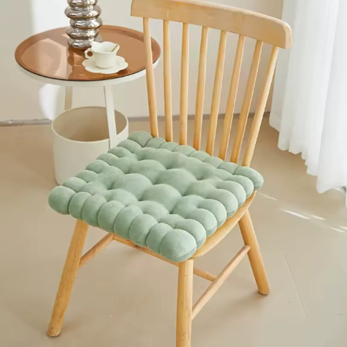 Coussin décoratif en forme de biscuit carré sur une chaise en bois à coté d'une petite table