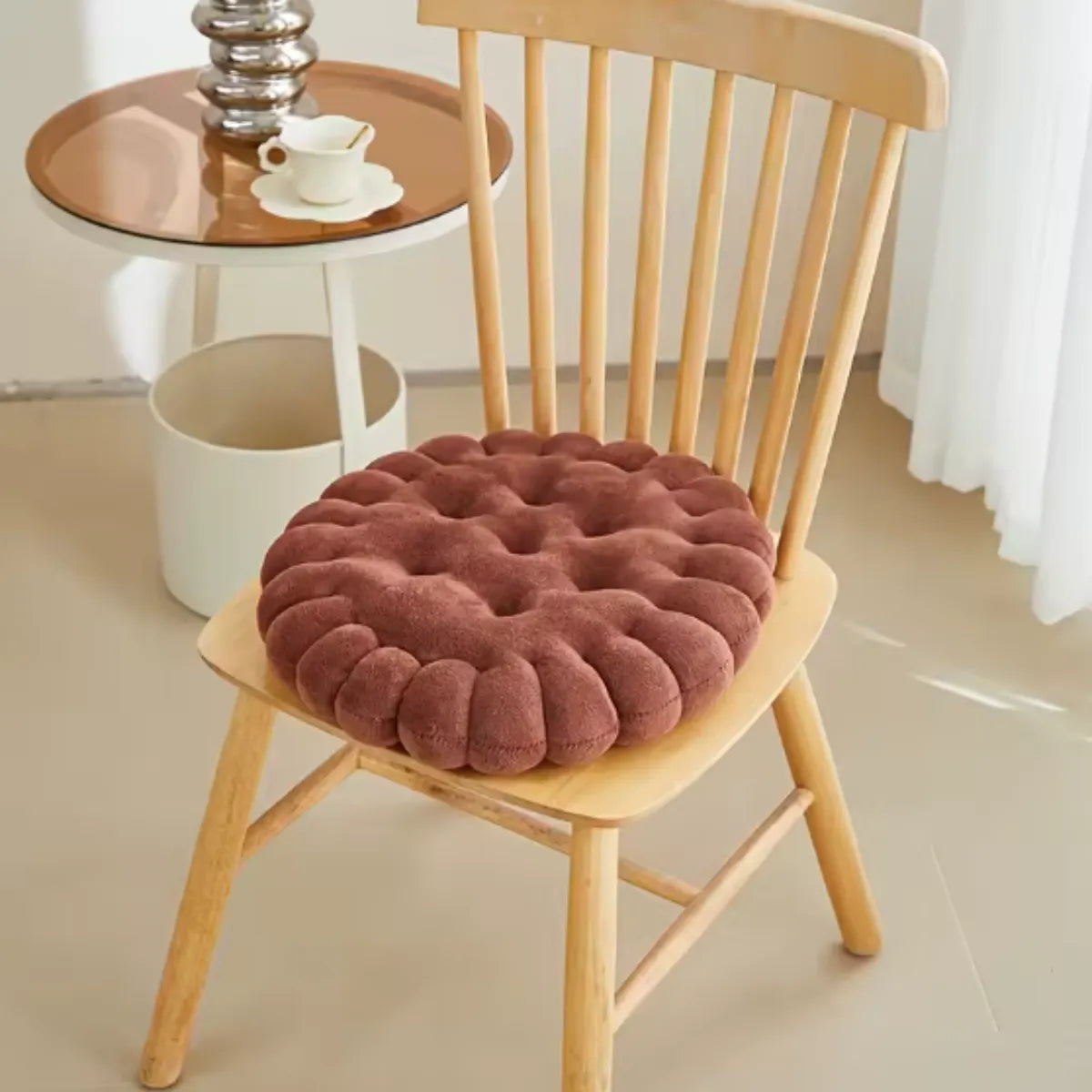 Coussin décoratif en forme de biscuit carré sur une chaise en bois à coté d'une petite table