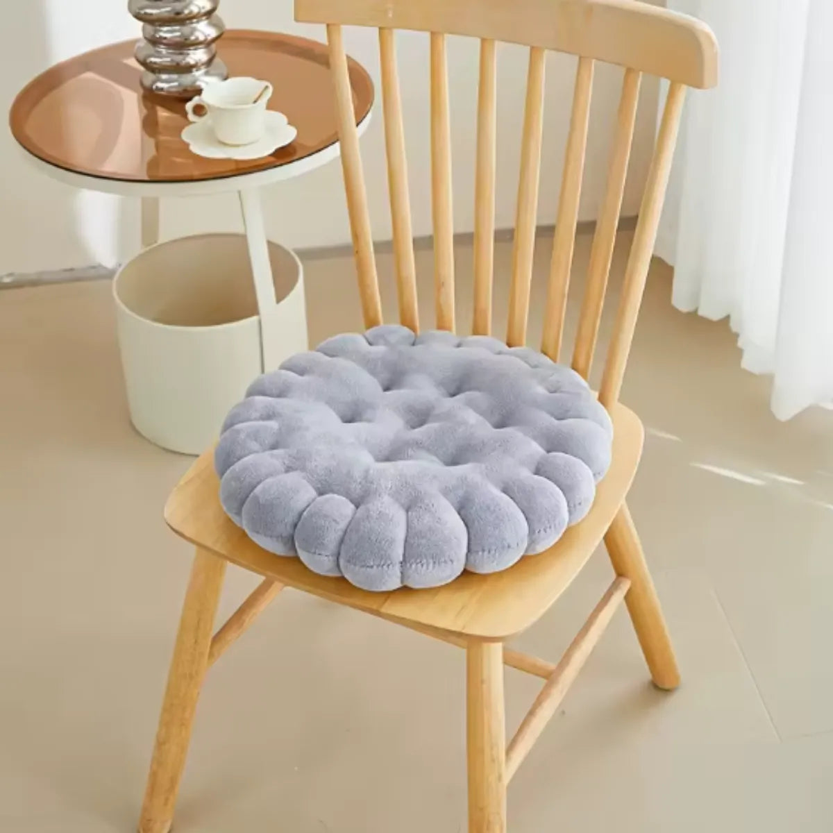 Coussin décoratif en forme de biscuit carré sur une chaise en bois à coté d'une petite table