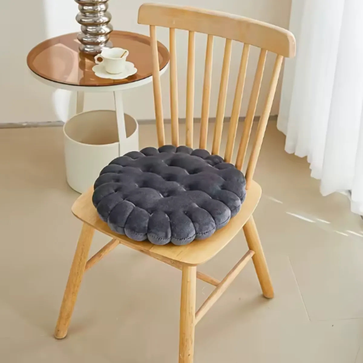 Coussin décoratif en forme de biscuit carré sur une chaise en bois à coté d'une petite table