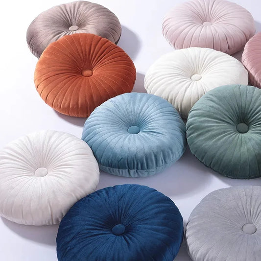 Coussins ronds forme citrouille avec bouton central, présentés en plusieurs coloris sur fond blanc