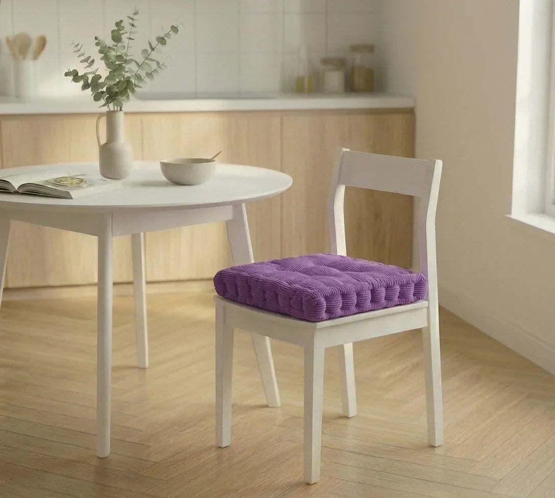Chaise blanche avec un coussin de chaise épais à motifs côtelés, placée dans une cuisine lumineuse au sol en bois clair.