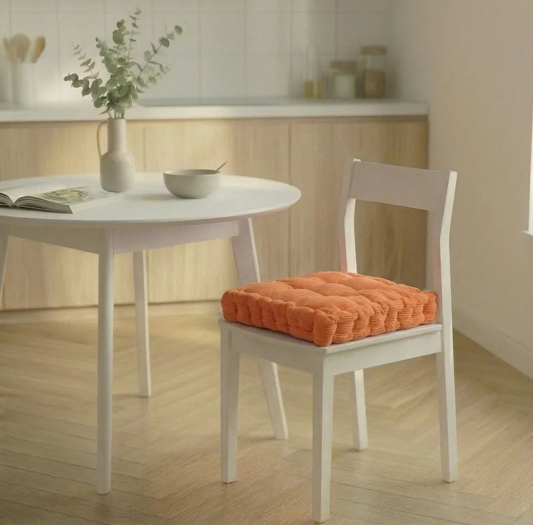 Chaise blanche avec un coussin de chaise épais à motifs côtelés, placée dans une cuisine lumineuse au sol en bois clair.