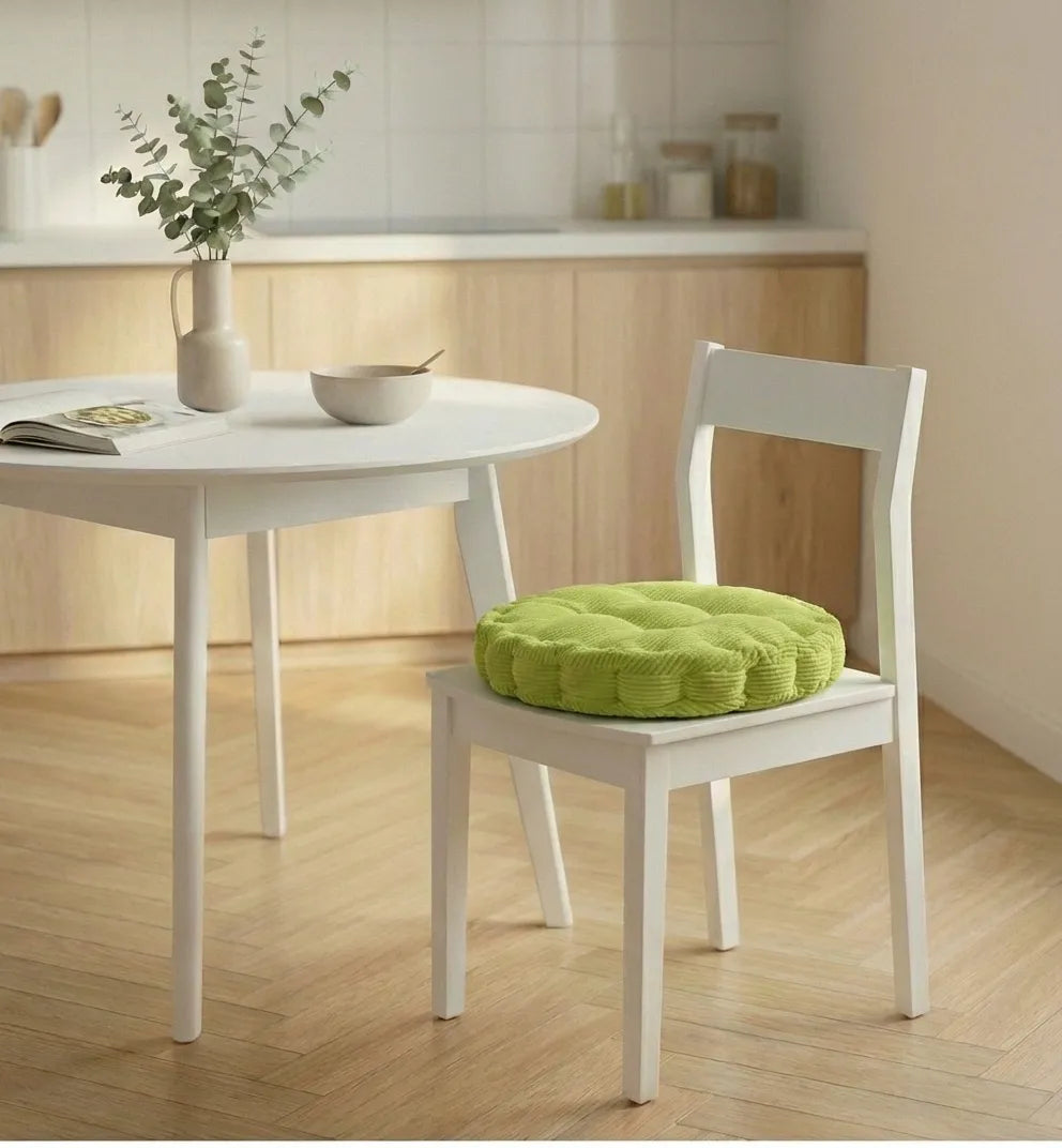 Chaise blanche avec un coussin de chaise épais à motifs côtelés, placée dans une cuisine lumineuse au sol en bois clair.
