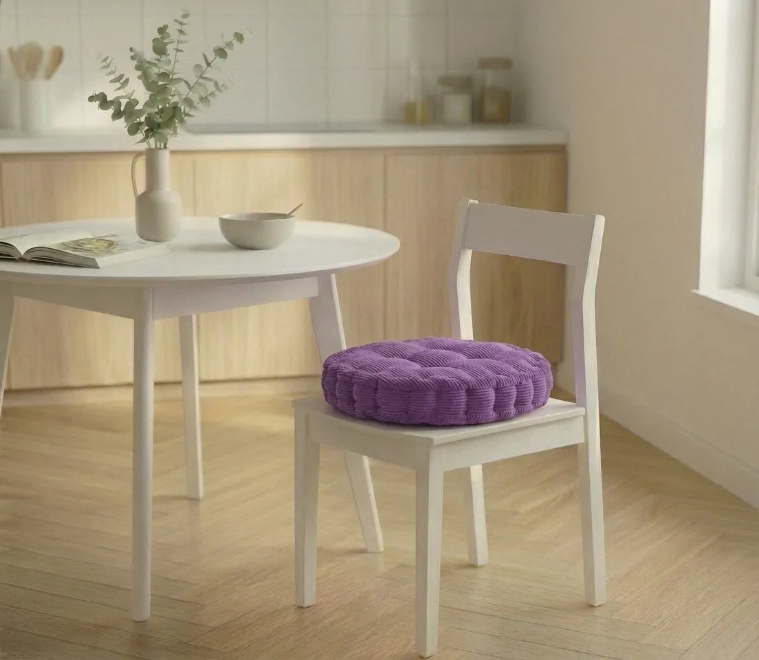 Chaise blanche avec un coussin de chaise épais à motifs côtelés, placée dans une cuisine lumineuse au sol en bois clair.